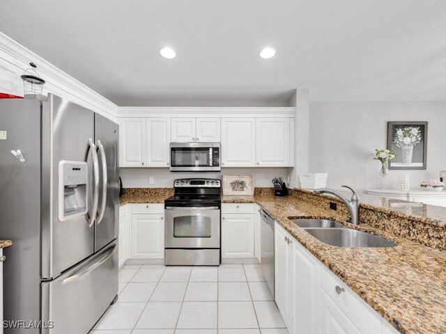 kitchen with appliances with stainless steel finishes, sink, light stone counters, and white cabinets