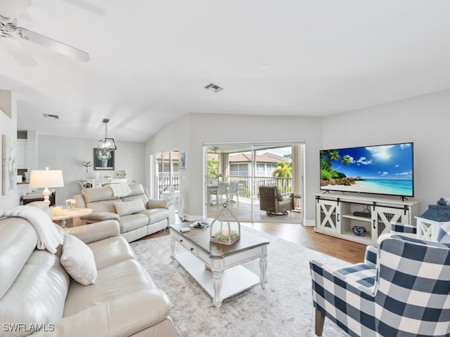 living room with ceiling fan, light hardwood / wood-style flooring, and lofted ceiling