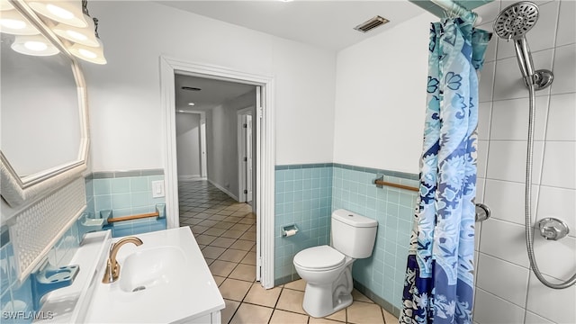 bathroom with vanity, tile patterned floors, tile walls, toilet, and a shower with shower curtain