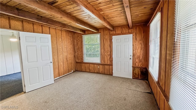 unfurnished bedroom featuring light colored carpet, wooden walls, beam ceiling, and wooden ceiling