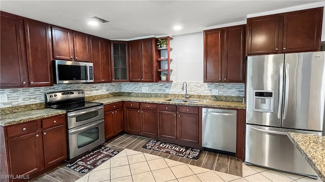 kitchen featuring light stone counters, sink, backsplash, hardwood / wood-style flooring, and stainless steel appliances