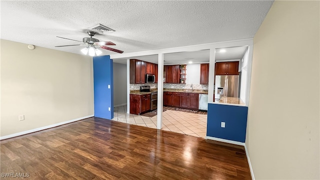 kitchen with ceiling fan, light hardwood / wood-style flooring, sink, appliances with stainless steel finishes, and a textured ceiling