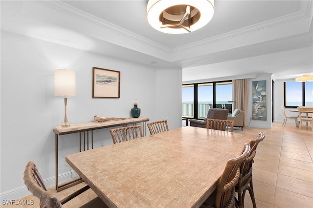 dining area featuring crown molding, a tray ceiling, a wealth of natural light, and light tile patterned floors