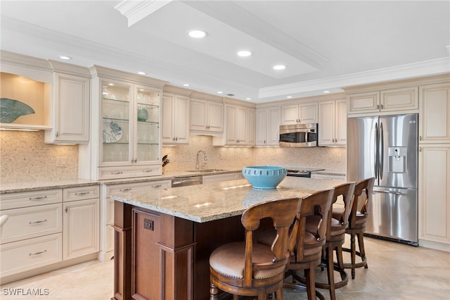 kitchen with cream cabinets, a center island, light stone countertops, and stainless steel appliances