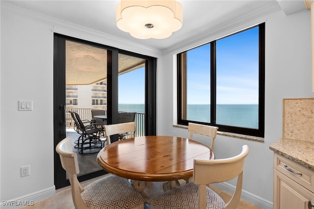 tiled dining space featuring crown molding and a water view