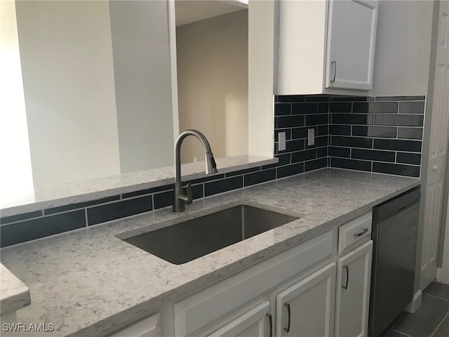 kitchen with white cabinets, sink, stainless steel dishwasher, light stone countertops, and decorative backsplash