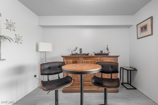 bar featuring a textured ceiling and light hardwood / wood-style floors