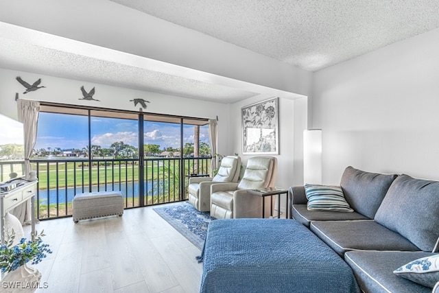 living room with light wood-type flooring, a textured ceiling, and a water view