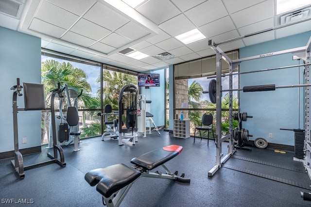 workout area featuring floor to ceiling windows, a drop ceiling, and plenty of natural light