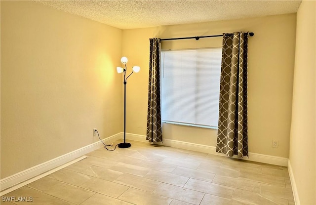 tiled empty room with a textured ceiling