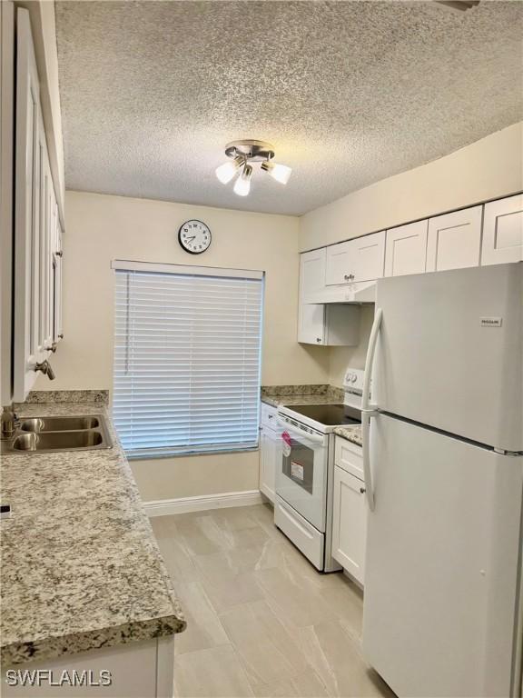 kitchen featuring white cabinetry, sink, white appliances, and a textured ceiling