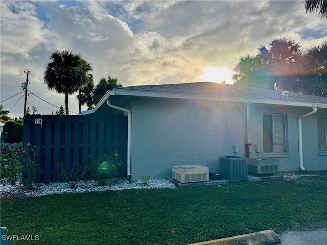 view of side of property with central AC unit and a lawn