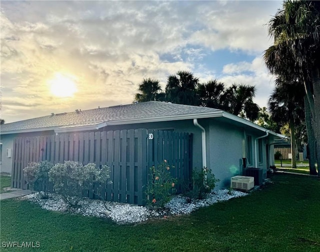 property exterior at dusk featuring a lawn