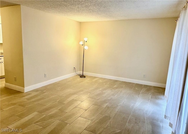 spare room featuring a textured ceiling and light hardwood / wood-style flooring