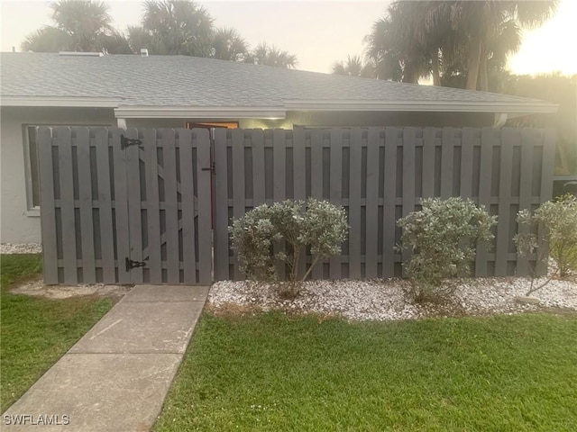 gate at dusk featuring a yard