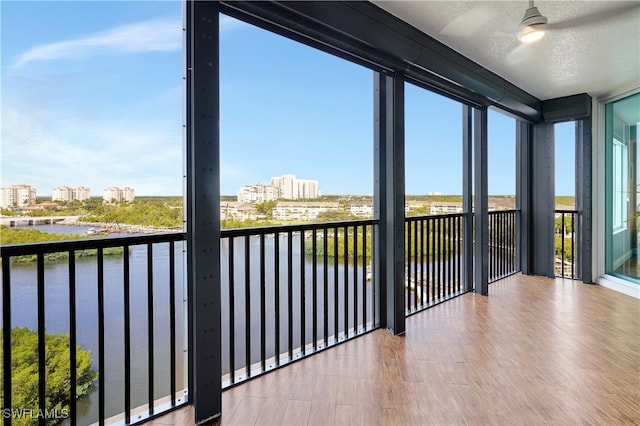 unfurnished sunroom featuring ceiling fan and a water view