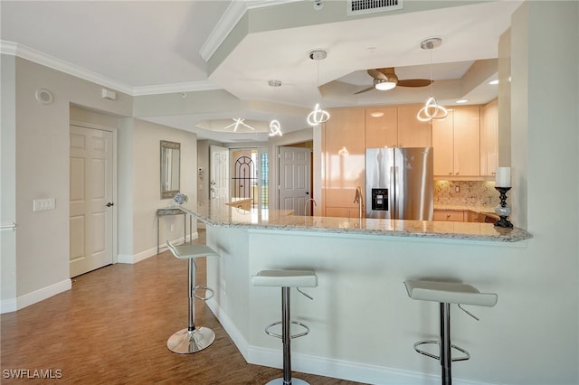 kitchen with light hardwood / wood-style flooring, decorative light fixtures, light stone countertops, stainless steel refrigerator with ice dispenser, and kitchen peninsula