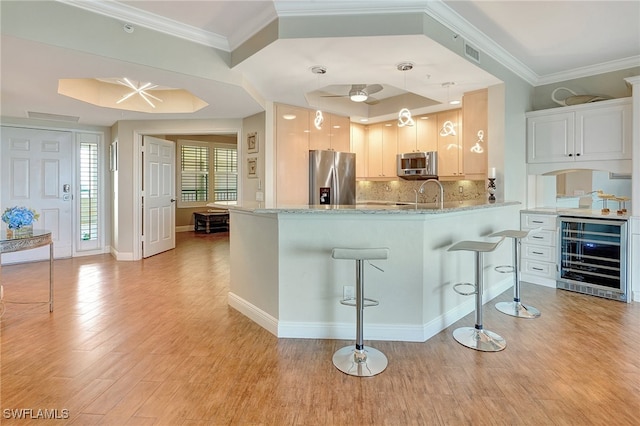 kitchen with appliances with stainless steel finishes, beverage cooler, white cabinetry, and a kitchen breakfast bar