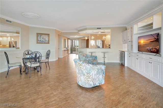 living room with ornamental molding, wine cooler, and light hardwood / wood-style flooring