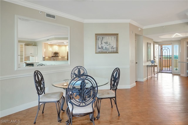 dining area with ornamental molding and light hardwood / wood-style flooring