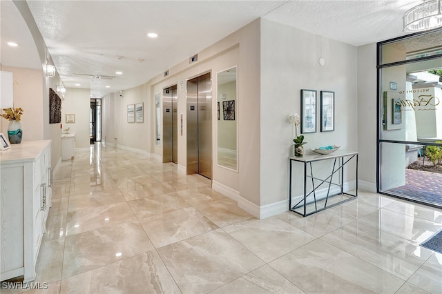 corridor with a textured ceiling, elevator, and a healthy amount of sunlight