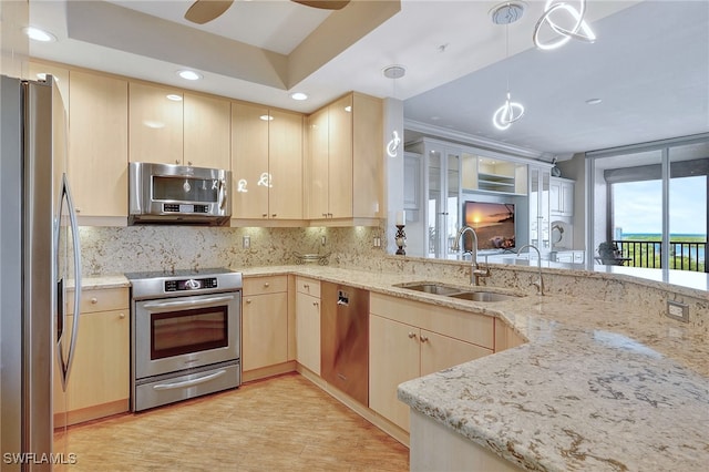 kitchen featuring light stone counters, light brown cabinets, sink, kitchen peninsula, and stainless steel appliances