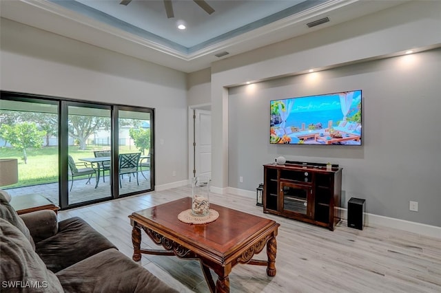 living room with a high ceiling, a raised ceiling, light hardwood / wood-style floors, and ceiling fan