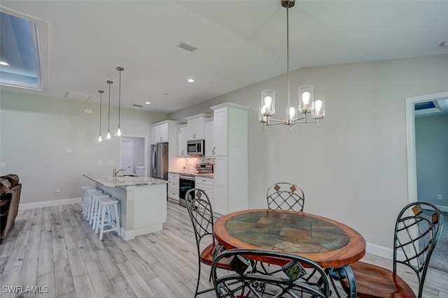 dining area featuring a notable chandelier, lofted ceiling, light hardwood / wood-style floors, and sink