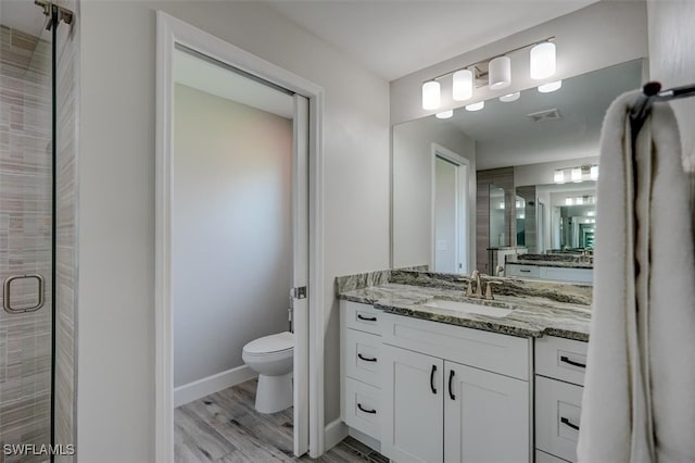 bathroom featuring vanity, toilet, an enclosed shower, and hardwood / wood-style flooring