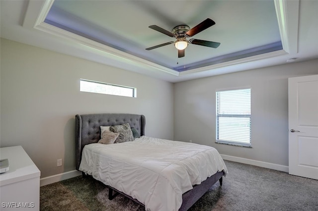 carpeted bedroom with ceiling fan and a tray ceiling