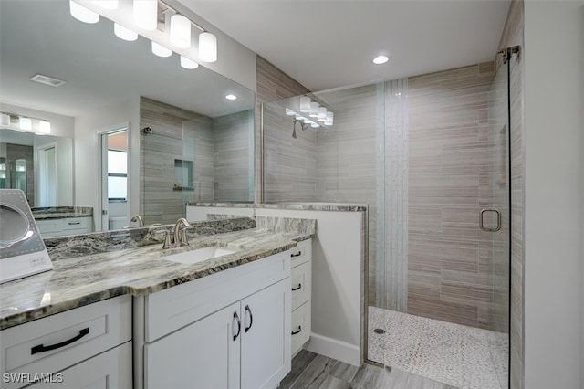 bathroom with walk in shower, vanity, and hardwood / wood-style floors