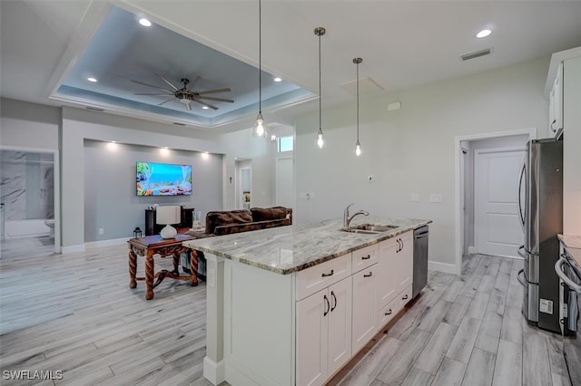 kitchen with hanging light fixtures, a tray ceiling, stainless steel appliances, and white cabinets