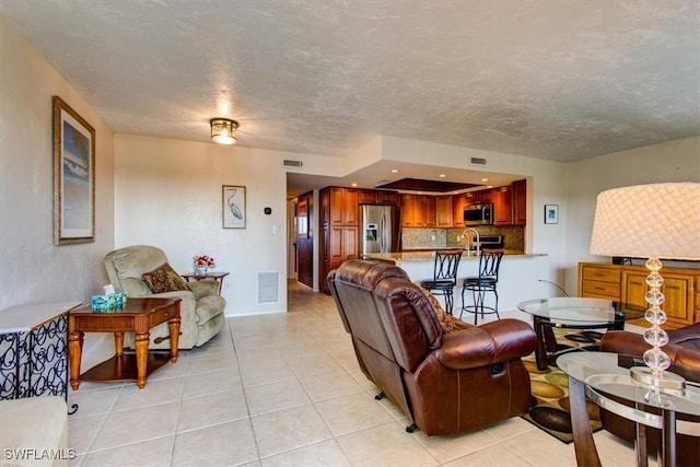 living room with sink, light tile patterned floors, and a textured ceiling