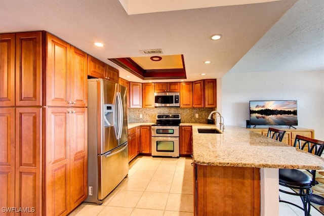 kitchen featuring decorative backsplash, a breakfast bar area, sink, stainless steel appliances, and kitchen peninsula