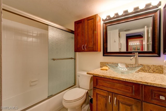 full bathroom featuring shower / bath combination with glass door, vanity, toilet, and a textured ceiling