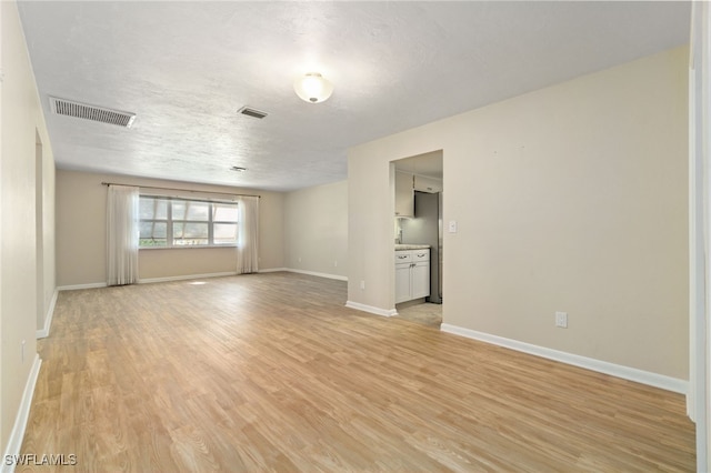 unfurnished room with light hardwood / wood-style floors and a textured ceiling