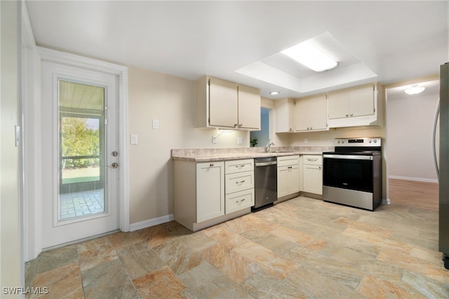 kitchen featuring a raised ceiling, white cabinetry, sink, and appliances with stainless steel finishes