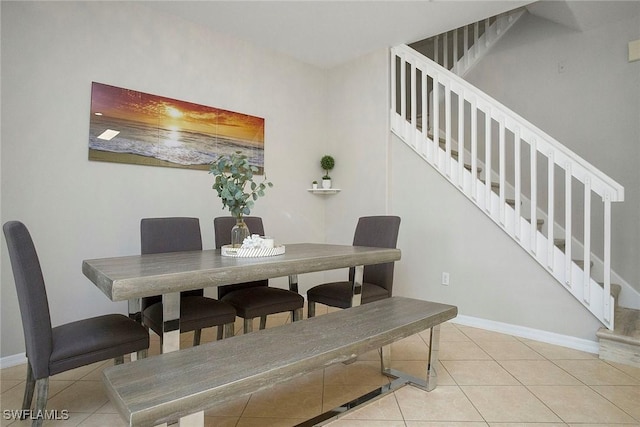 dining space featuring baseboards, tile patterned floors, and stairs