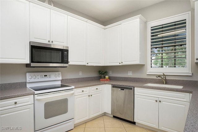 kitchen with light tile patterned floors, a sink, white cabinetry, and appliances with stainless steel finishes