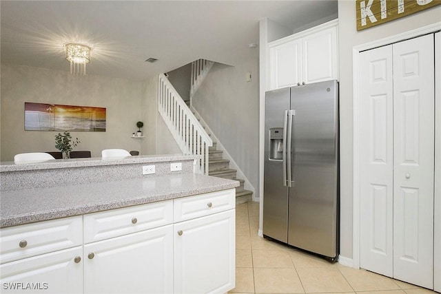 kitchen with white cabinets, stainless steel fridge, baseboards, light stone countertops, and light tile patterned floors