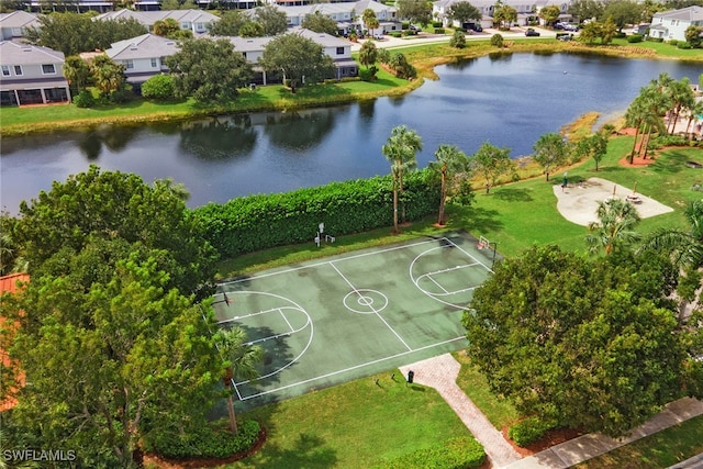 view of basketball court with a water view and a yard