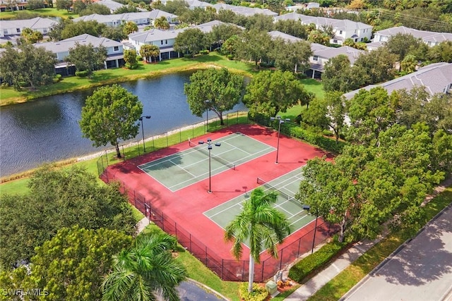 view of sport court with a residential view, a water view, and fence