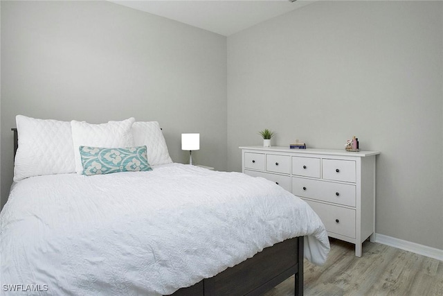 bedroom featuring baseboards and light wood finished floors