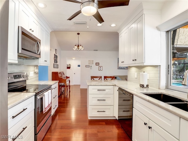 kitchen with decorative light fixtures, stainless steel appliances, dark hardwood / wood-style floors, and white cabinetry