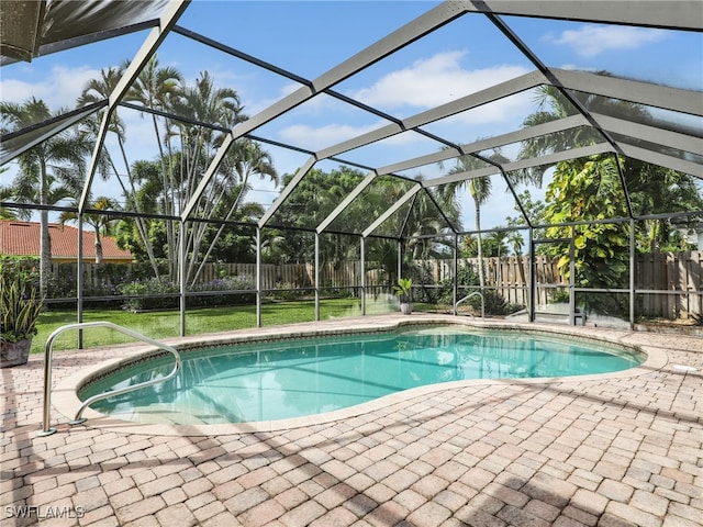 view of pool with glass enclosure, a yard, and a patio area