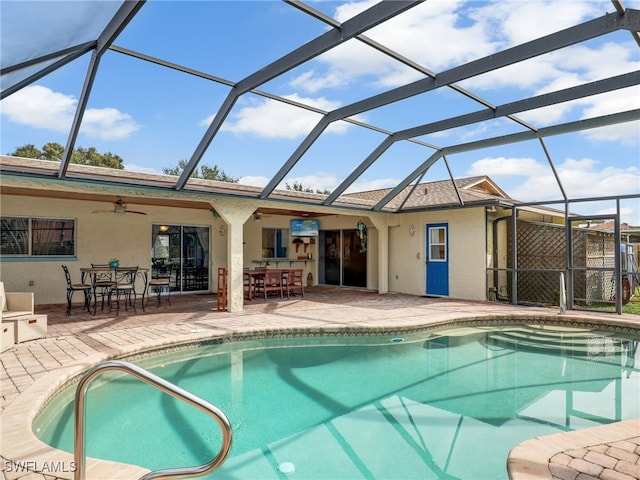 view of swimming pool featuring ceiling fan, glass enclosure, and a patio