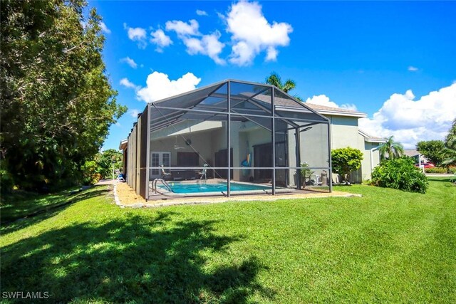 rear view of property with a yard and glass enclosure