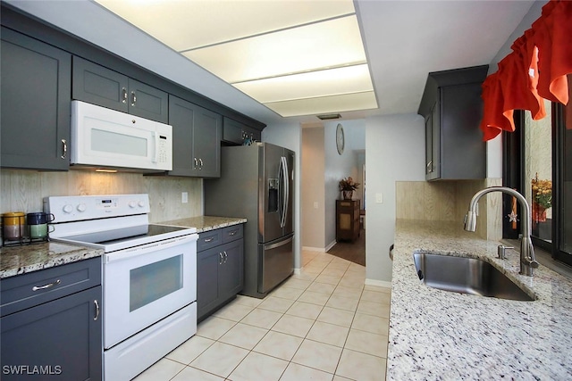 kitchen featuring sink, decorative backsplash, light stone counters, and white appliances