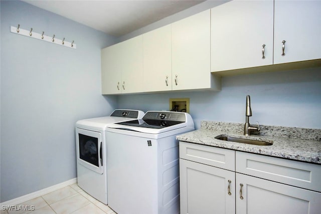 clothes washing area featuring light tile patterned floors, cabinets, sink, and washing machine and clothes dryer