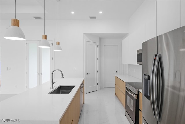 kitchen with appliances with stainless steel finishes, sink, a large island, pendant lighting, and white cabinets